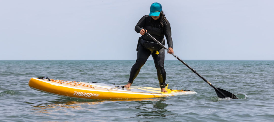 Woman performs a SUP pivot turn on a Thurso Surf paddleboard