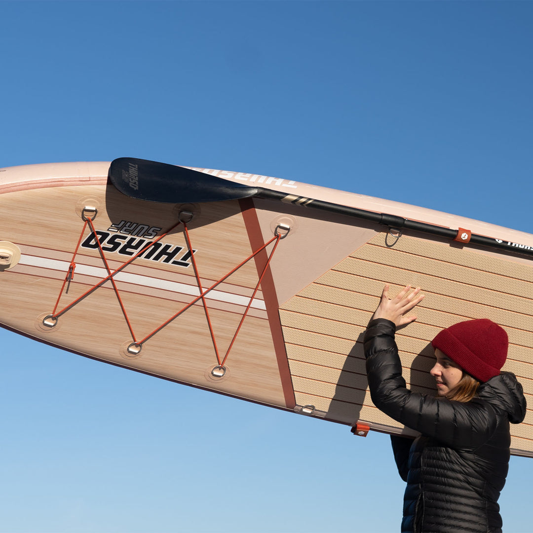 woman carrying thurso surf 2023 waterwalker 132 SUP paddle board crimson