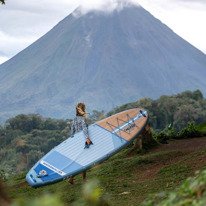 A woman carries THURO SURF Waterwalker all-around SUP 132 Dusk