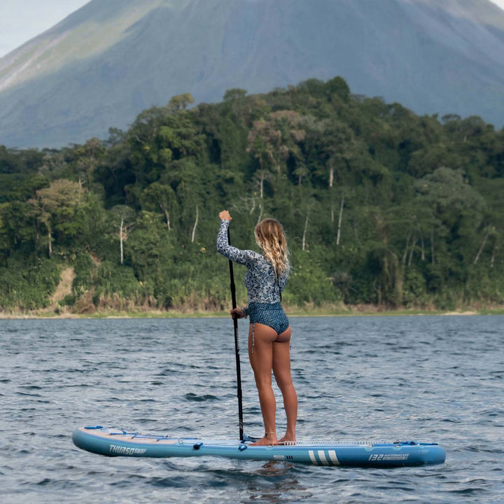 A woman stand on Thurso Surf Waterwalker 132 all-around SUP Dusk on Lake