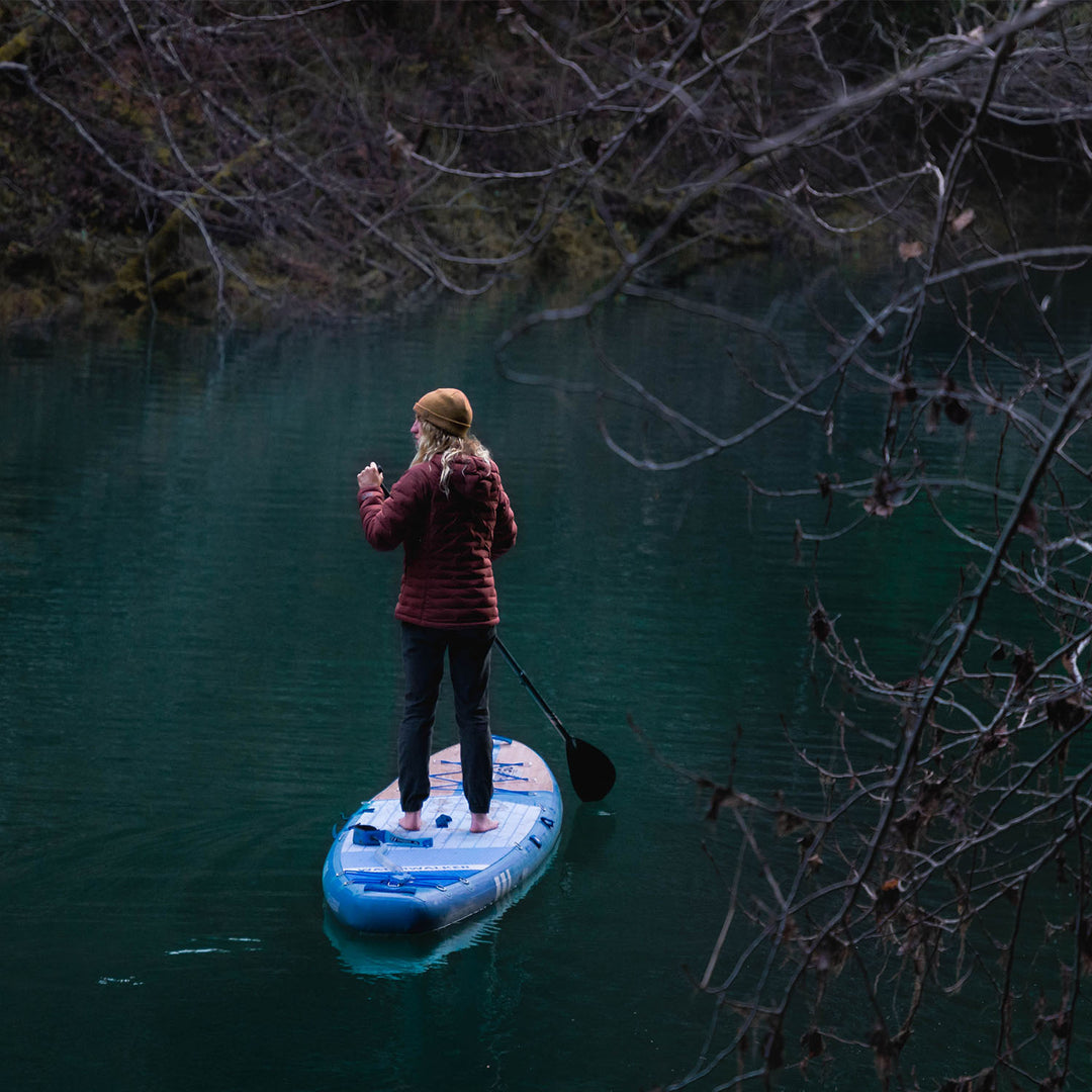 A woman standing on the thurso surf inflatable stand up board on the lake