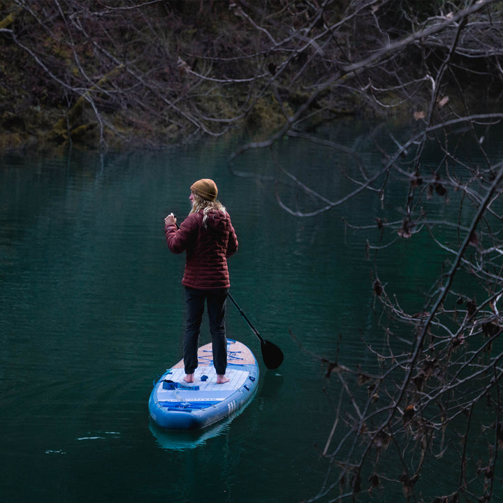 A woman standing on the thurso surf inflatable stand up board on the lake