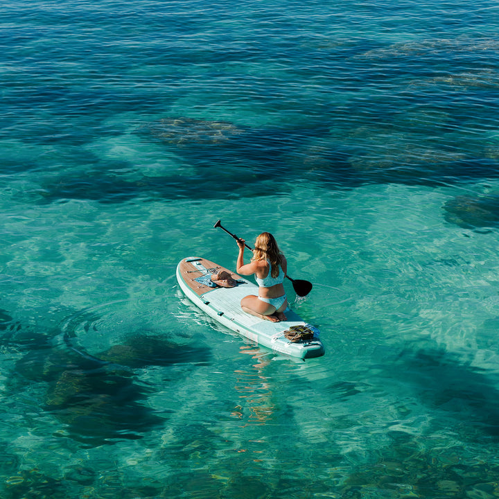 Woman paddleboarding on a clear blue ocean with turquoise thurso surf paddleboard