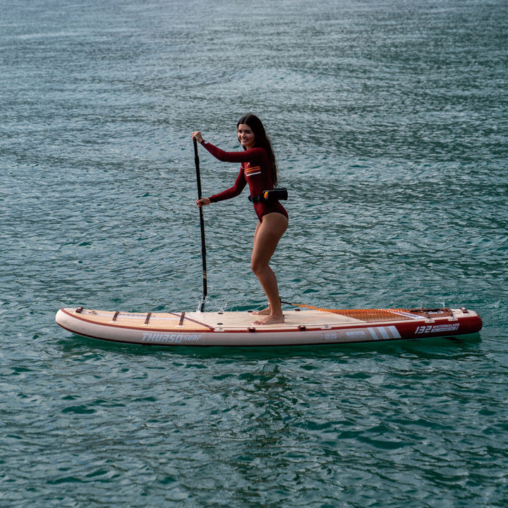 Woman paddleboarding on a calm body of water with thurso surf crimson paddleboard